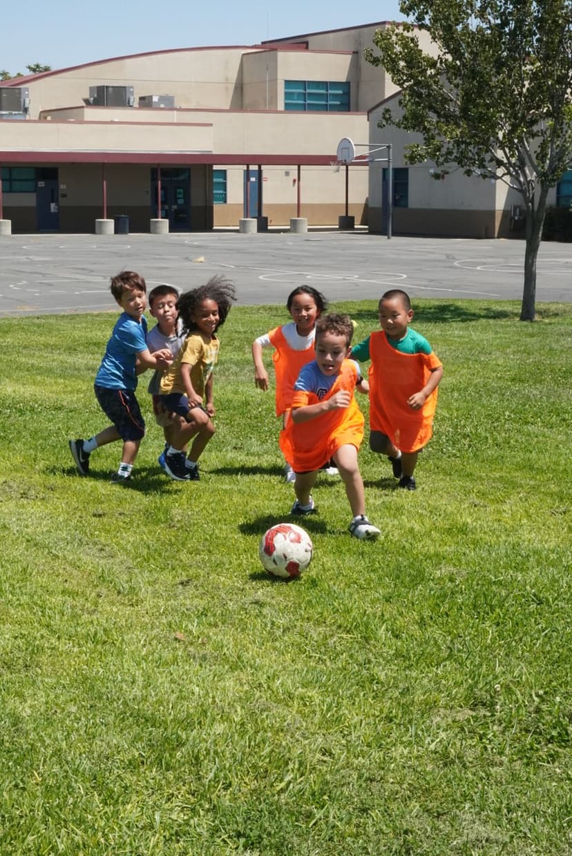 Young students chasing a soccer ball across the grass